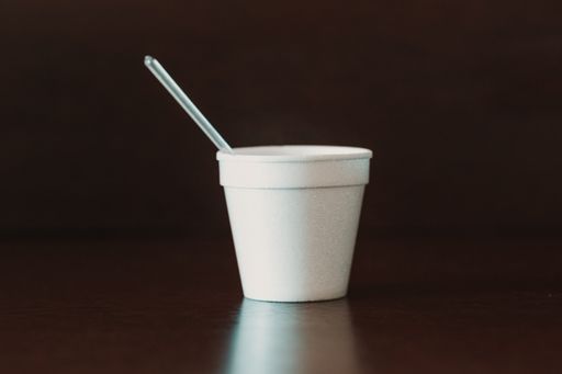 A selective focus shot of a small white cup with a spoon on a wooden table