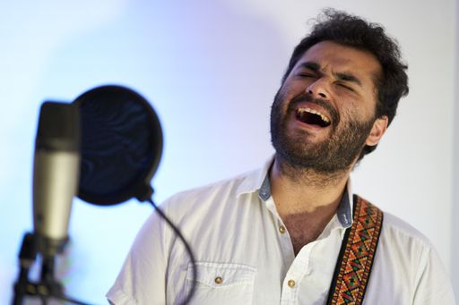 A professional passionate male musician with electric guitar singing enthusiastically and recording in a studio