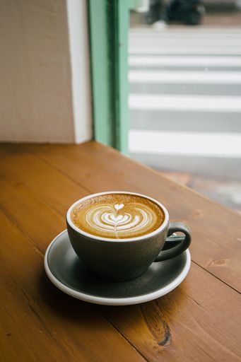 A vertical shot of coffee with grey cup above wooden table in a coffee shop