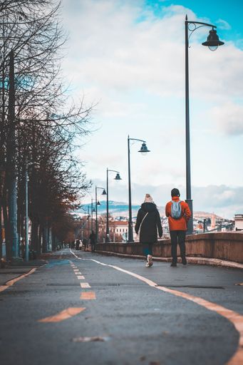 A vertical shot of people walking along a narrow street with vintage street lights
