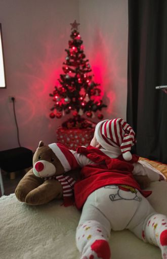 Cute toddler laying on the couch and watching a decorated Christmas tree with red lighting