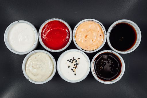 A high angle shot of small bowls filled with different flavored sauces on a table
