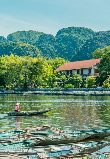 A vertical shot of traditional boats on the river in the town of Tam Coc near Ninh Binh, Vietnam