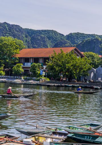 A vertical shot of traditional boats sailing on the river in the town of Tam Coc near Ninh Binh, Vietnam