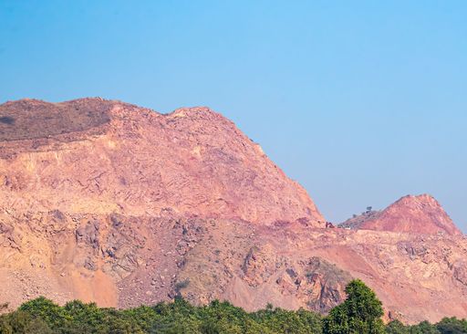 A scenic landscape with a small red mountain against a blue sky