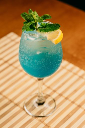 A vertical shot of a vibrant blue alcoholic beverage garnished with a lemon slice