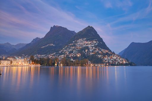 A stunning view of Lugano city in Switzerland, with the sunset over the tranquil lake