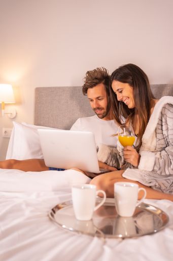 A happy loving couple relaxing in the bedroom and using laptop