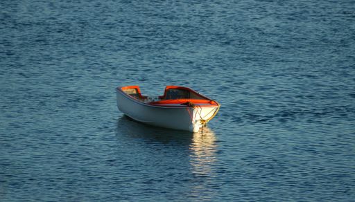 An empty boat with its reflection on the water in Waipu River, New Zealand