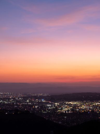 Vibrant sunset with purple, blue, yellow, orange, and red colours over a twinkling city