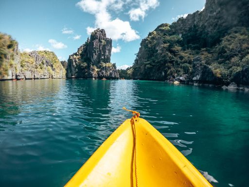 A beautiful view of a yellow boat, hills and the water at the El Nido resort in the Philippines