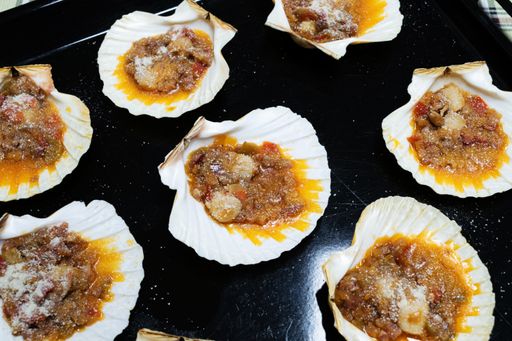 View of a Scallops with onion, pieces of ham, pepper, tomato sauce and breadcrumbs. Scallops Galician