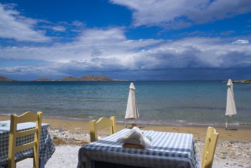 A beautiful shot of tables of a restaurant on the coastline under the cloudy sky