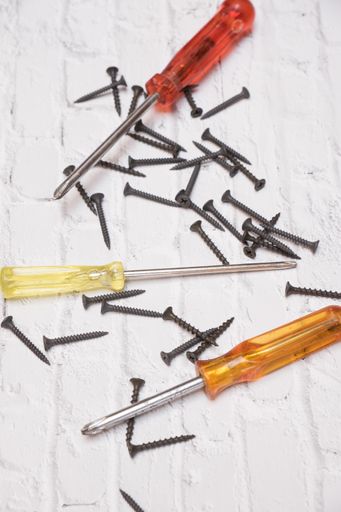 A vertical shot of nails and pliers on a white stone surface