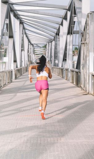 A young female in sporty clothes running in street