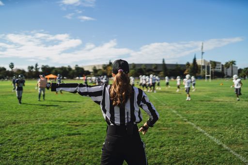 A closeup of an American football referee standing on the field watching the game.