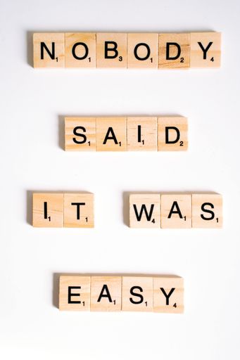 A vertical shot of scrabble letters spelling the message "nobody said it was easy" on white background