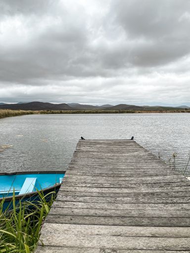 View from a jetty on a cloudy day with blue boat on left side. Looking to the future (concept)