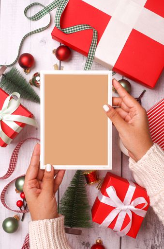 A vertical shot of an empty frame in a female hands over the Christmas decorations