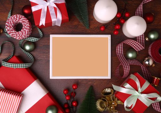 An empty frame on a wooden surface surrounded by the Christmas decorations