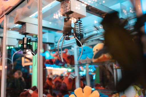 A selective focus shot of a claw crane machine game in an arcade