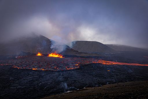 A large open crater emitting dark lava and smokey fog