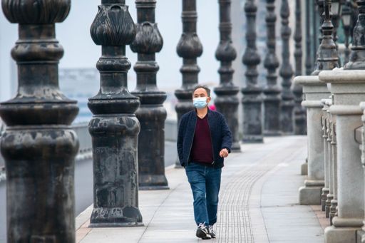 A mature man wearing a face mask walking along a sidewalk