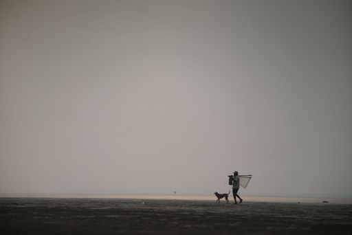 An evening worker walking on the beach with his dog