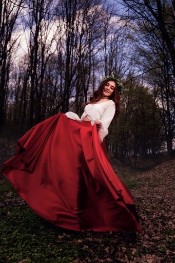 A fashionable young woman wearing a long red skirt a forest