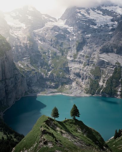 A beautiful view of a lake surrounded by rocky mountains and greenery in Switzerland