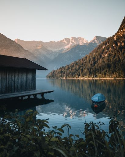 A boat in a lake near a cabin with rocky mountains in the background in Switzerland