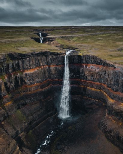 A breathtaking view of  Layer Falls surrounded by rocky cliffs in Iceland