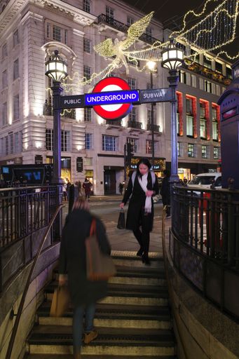 A vertical shot of people commuting on the stairs in Oxford Circus Tube Entrance with Christmas Lights in London, England