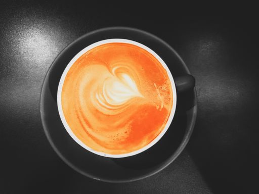 A closeup shot of a coffee latte art with heart-shaped in a black cup and saucer