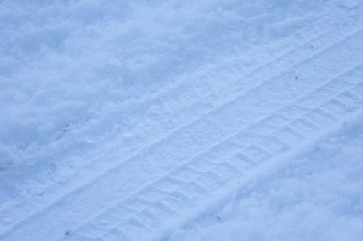 A beautiful white background of snowy ground with a trail of a car wheel