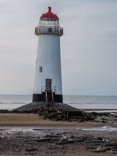 A vertical shot of the Point of Ayr lighthouse near the sea on a clouded day