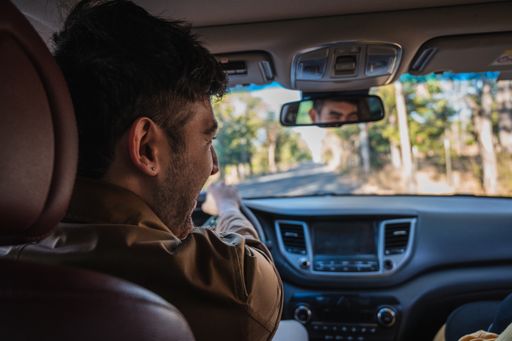A shallow focus of a young Hispanic male laughing while driving a modern car