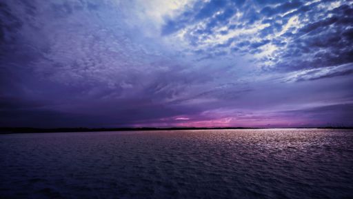 A beautiful lake with a tranquil blue body of water, adorned with clouds creating a tranquil, yet rainy atmosphere