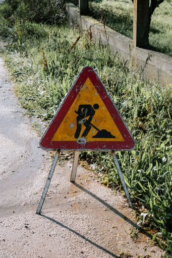 A vertical shot of a construction in progress sign next to a grass