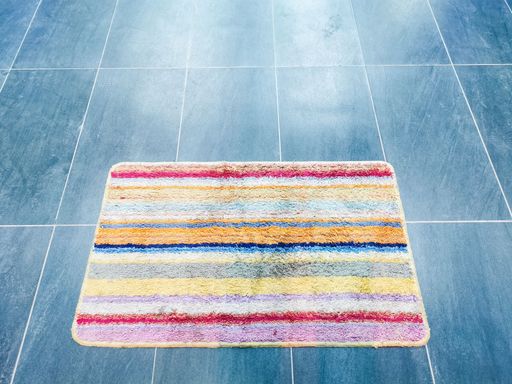 Colorful floor mate on the grey tiles. Selective focus.