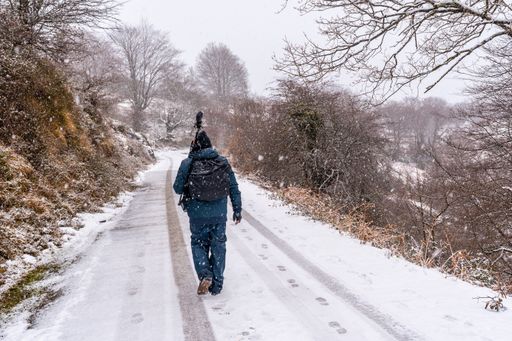 A young hiker with photography tools walking on the snowy road of Mount Aizkorri in Gipuzkoa