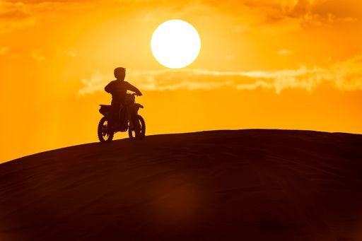 Silhouette man on a motorbike against the backdrop of the rising sun