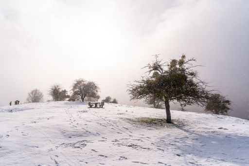 A bright shot of a picnic area with benches covered by snow on the peak of Mount Aizkorri in Gipuzkoa