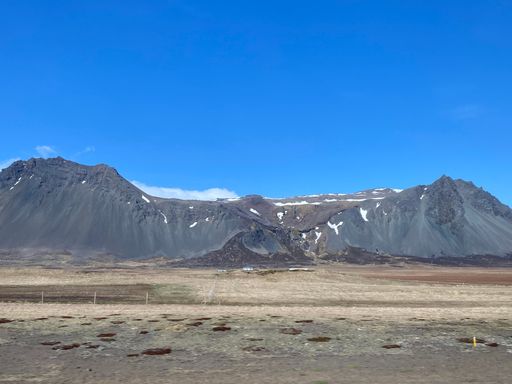 A barren landscape, with snow-capped mountains in the background, set against a vast expanse of land