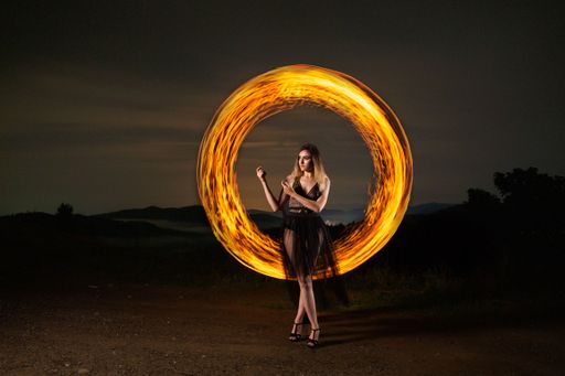 A beautiful shot of a young woman with swirling long exposure lights in the background in a forest