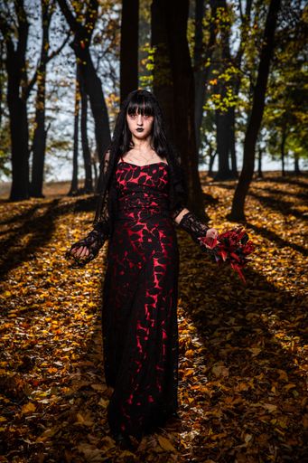 A vertical shot of a scary corpse bride in the autumn forest
