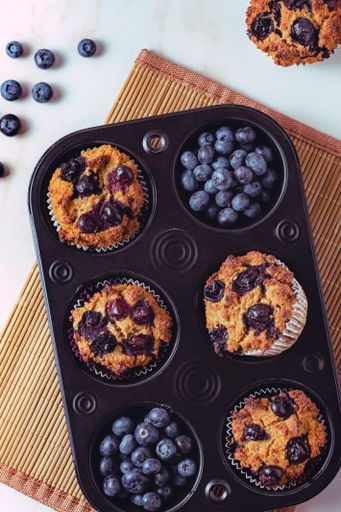 A vertical top view of the soft muffins studded with organic blueberries  on the kitchen board