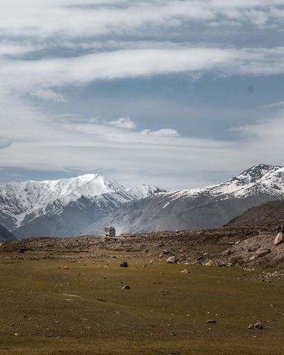 A white pick-up truck is parked on a gravel road in a mountainous landscape