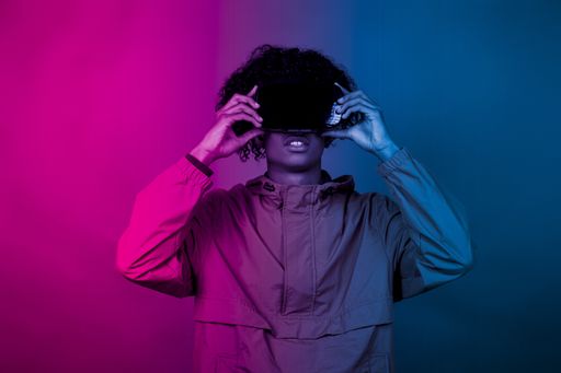 A young African male with VR glasses standing under the blue and purple lights