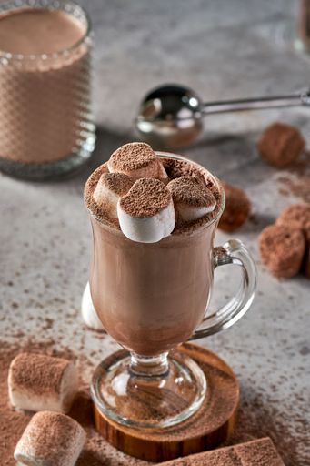 A glass of marshmallow latte with cocoa powder.